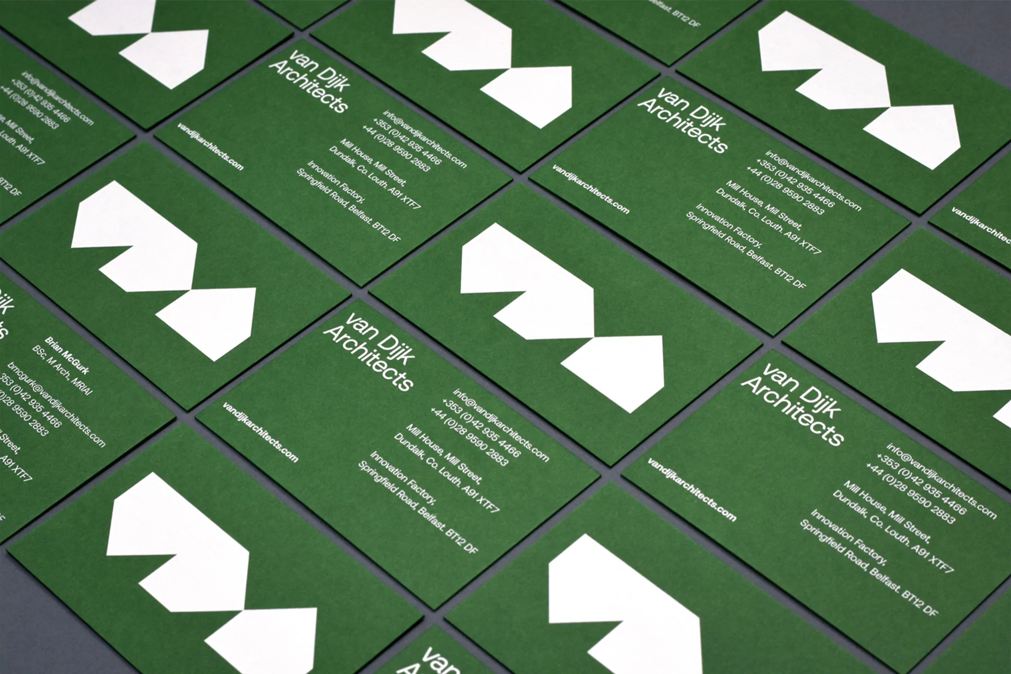 Multiple green business cards with white typography and geometric house logos laid out neatly in a grid.