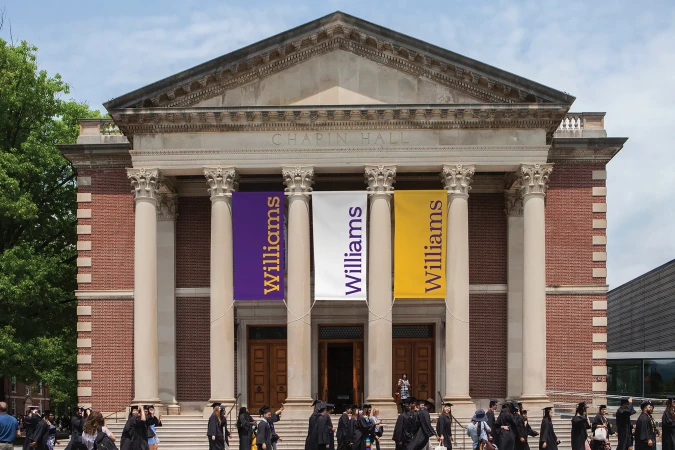 Chapin Hall at Williams College with banners, people in graduation gowns. Architectural landmark with classical columns and brick facade.