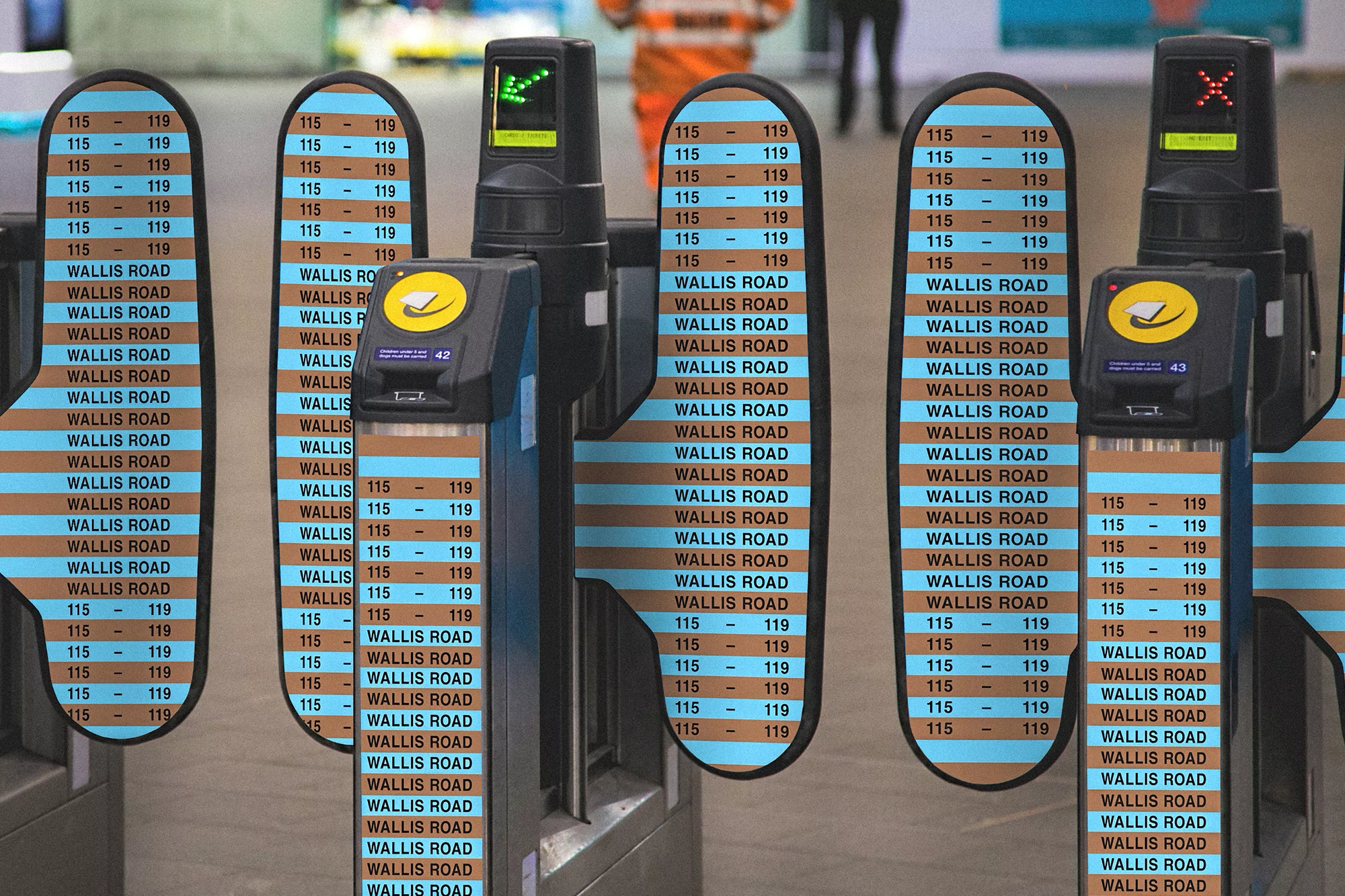 Automated transit gates at Wallis Road, with numbers and street names on barriers, in an indoor transit station environment.