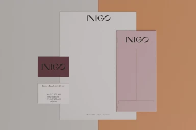 Flat lay of corporate stationery including letterhead, envelopes, and business cards featuring the Inigo brand identity on a split background