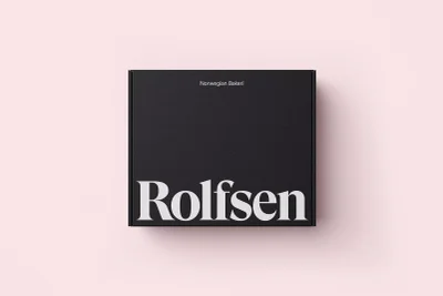 Top-down view of a black square packaging box with white typography branding set against a pale pink background