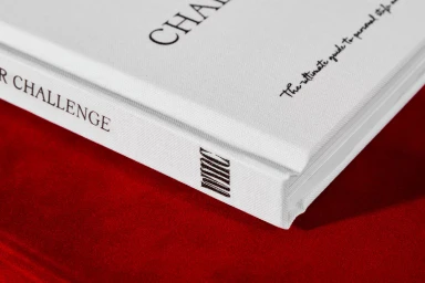 Close-up of white hardcover books with black typography resting on a rich red velvet surface