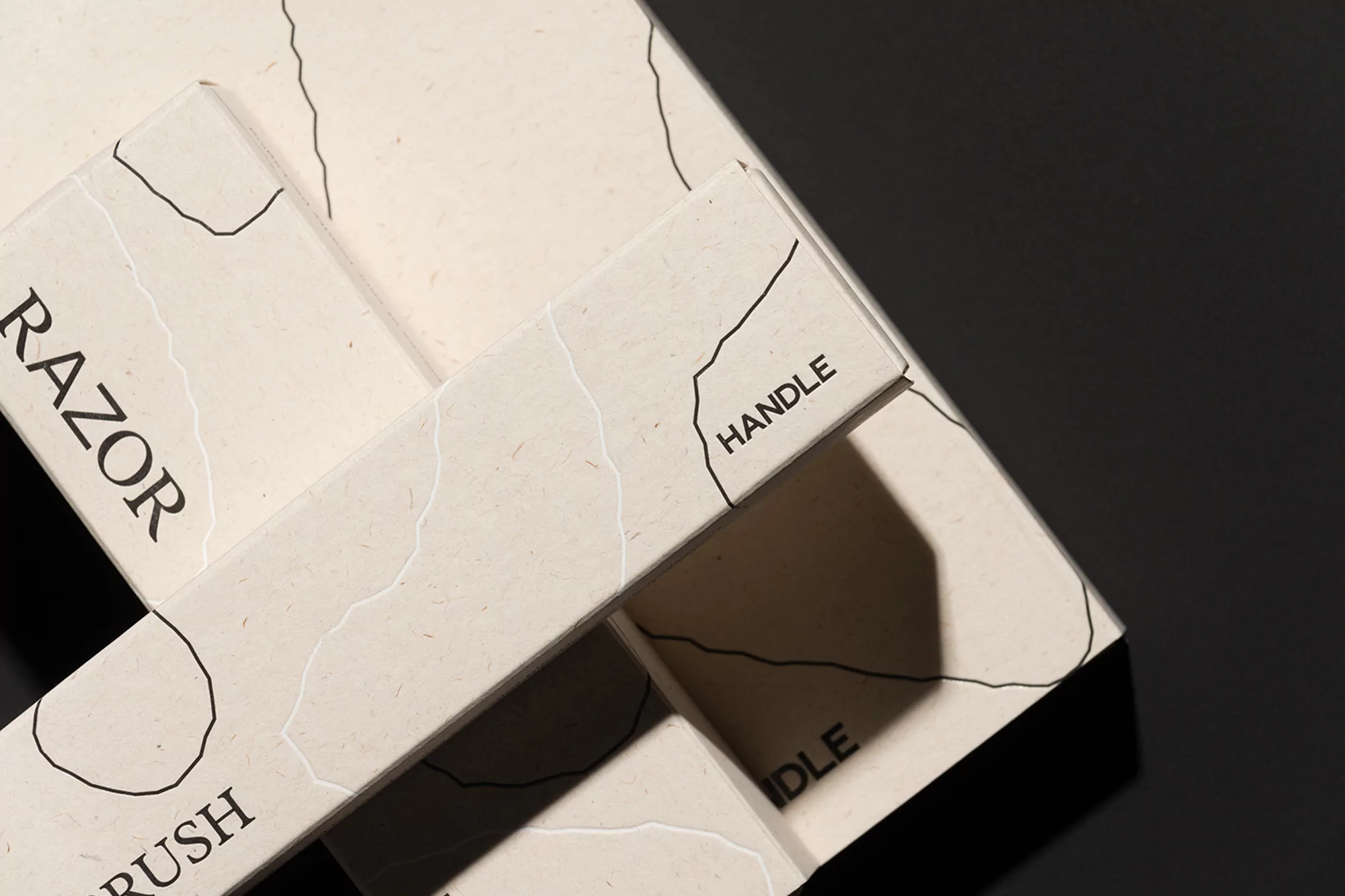 Close-up of bathroom accessories: a razor, toothbrush, and their handles are displayed, showcasing minimalist design on a dark surface.