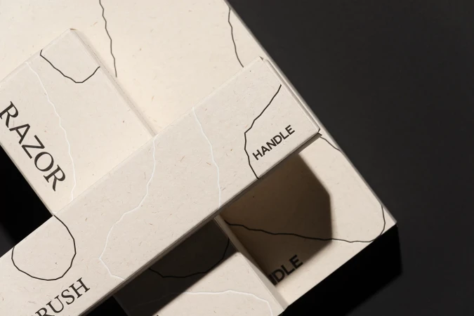 Close-up of bathroom accessories: a razor, toothbrush, and their handles are displayed, showcasing minimalist design on a dark surface.