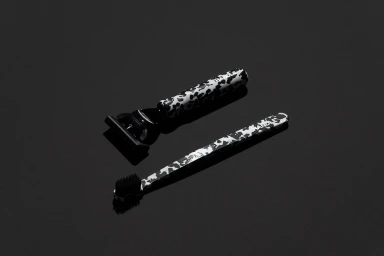 Black and white patterned razor and toothbrush displayed on a dark grey surface for the Handle brand identity project.