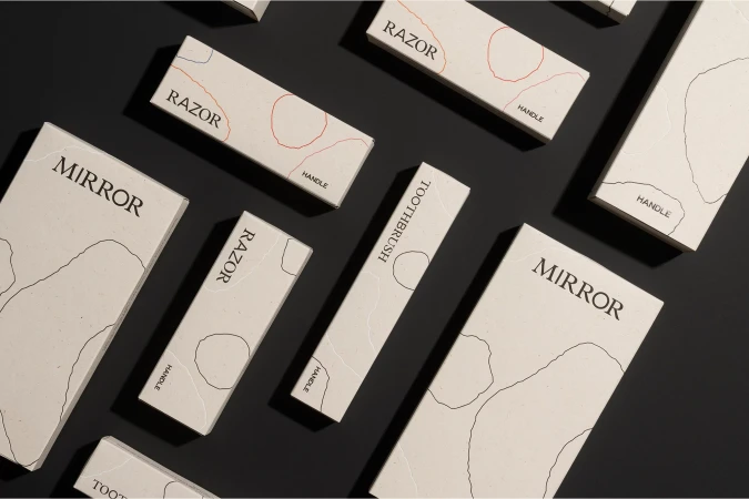 Flat lay of off-white paper product packaging boxes with minimalist typography and abstract line art on a dark surface.