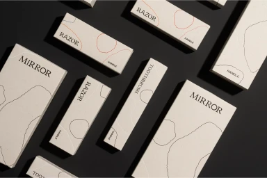 Flat lay of off-white paper product packaging boxes with minimalist typography and abstract line art on a dark surface.
