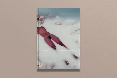 Book cover mockup titled AGUA featuring photography of a figure in water, set against a textured grey backdrop.