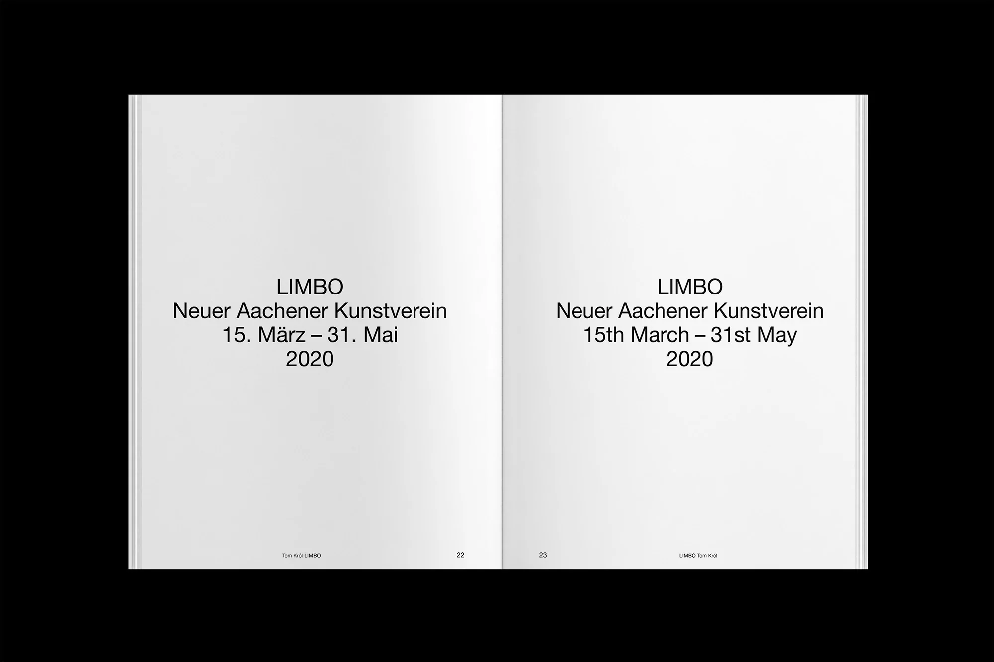 Opened book spread featuring text in English and German, black text on white pages, viewed overhead on a black background.