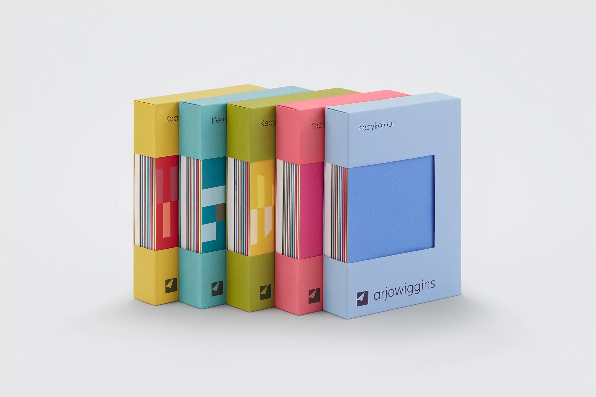 Close-up of a colorful assortment of Keaykolour paper swatch books standing on a light gray surface in a studio setting.