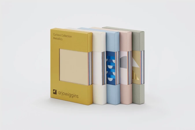 Five coloured paper swatch sample boxes standing upright in a row against a clean white seamless studio background.