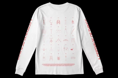 White long-sleeve t-shirt with red graphic illustrations on the back and text down the sleeves on a dark background.