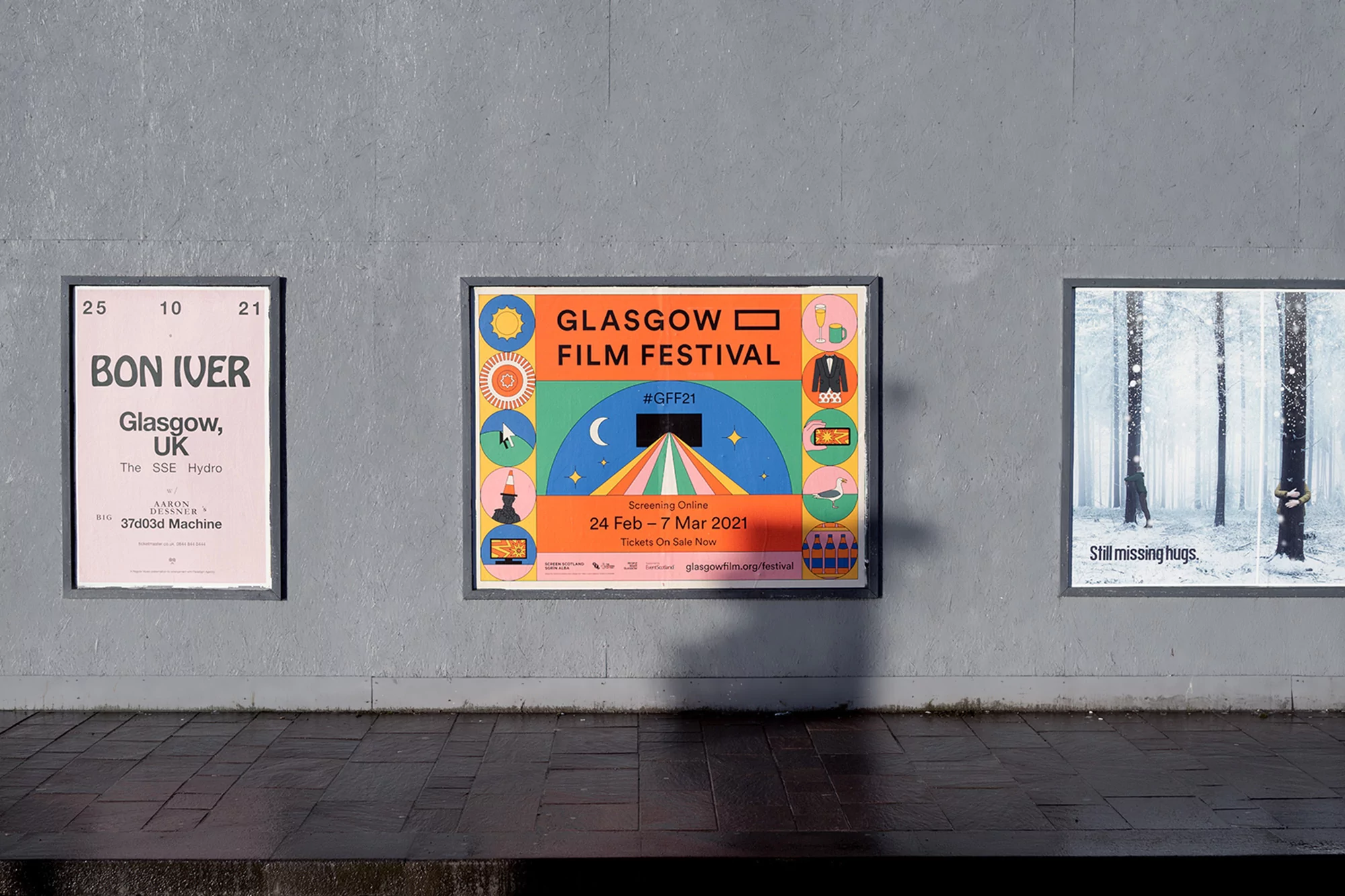 Three framed posters on a gray wall: Bon Iver concert, Glasgow Film Festival, and a winter scene, create a visual display.