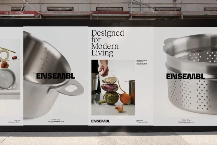 Out of home advertising posters for ENSEMBL showcasing stainless steel cookware and fresh produce on a city street.