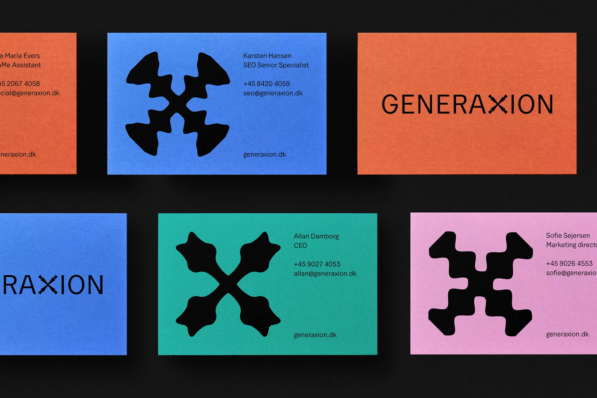 Collection of colorful business cards on a dark surface featuring the GENERAXION logo, contact information, and a modern, minimalist design aesthetic.