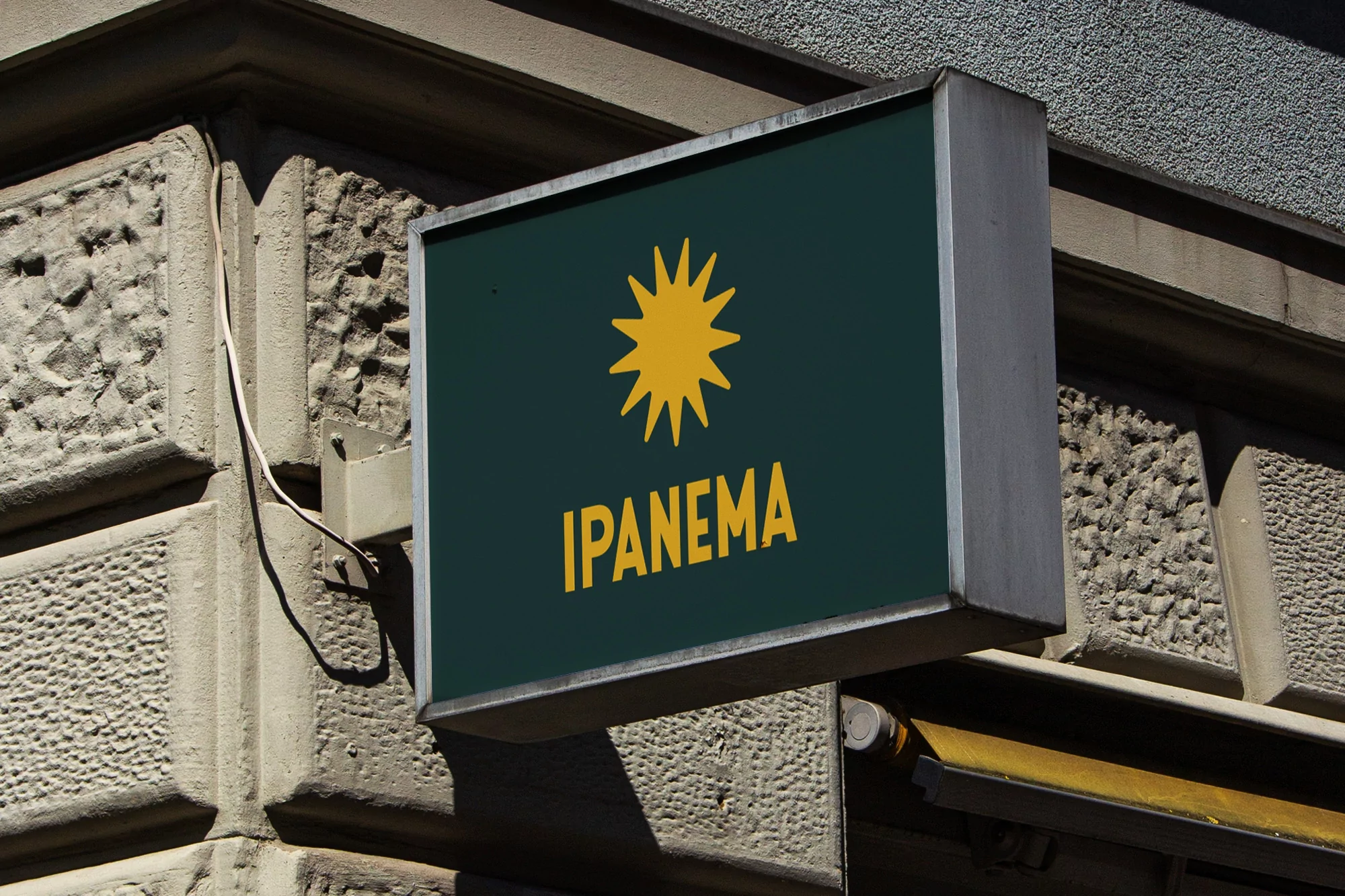 Outdoor sign displaying the Ipanema brand name in yellow lettering with a stylized sun-like starburst on a dark green background.