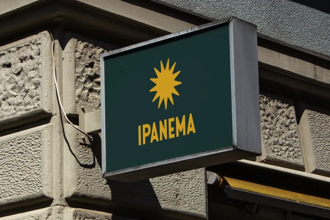 Outdoor sign displaying the Ipanema brand name in yellow lettering with a stylized sun-like starburst on a dark green background.