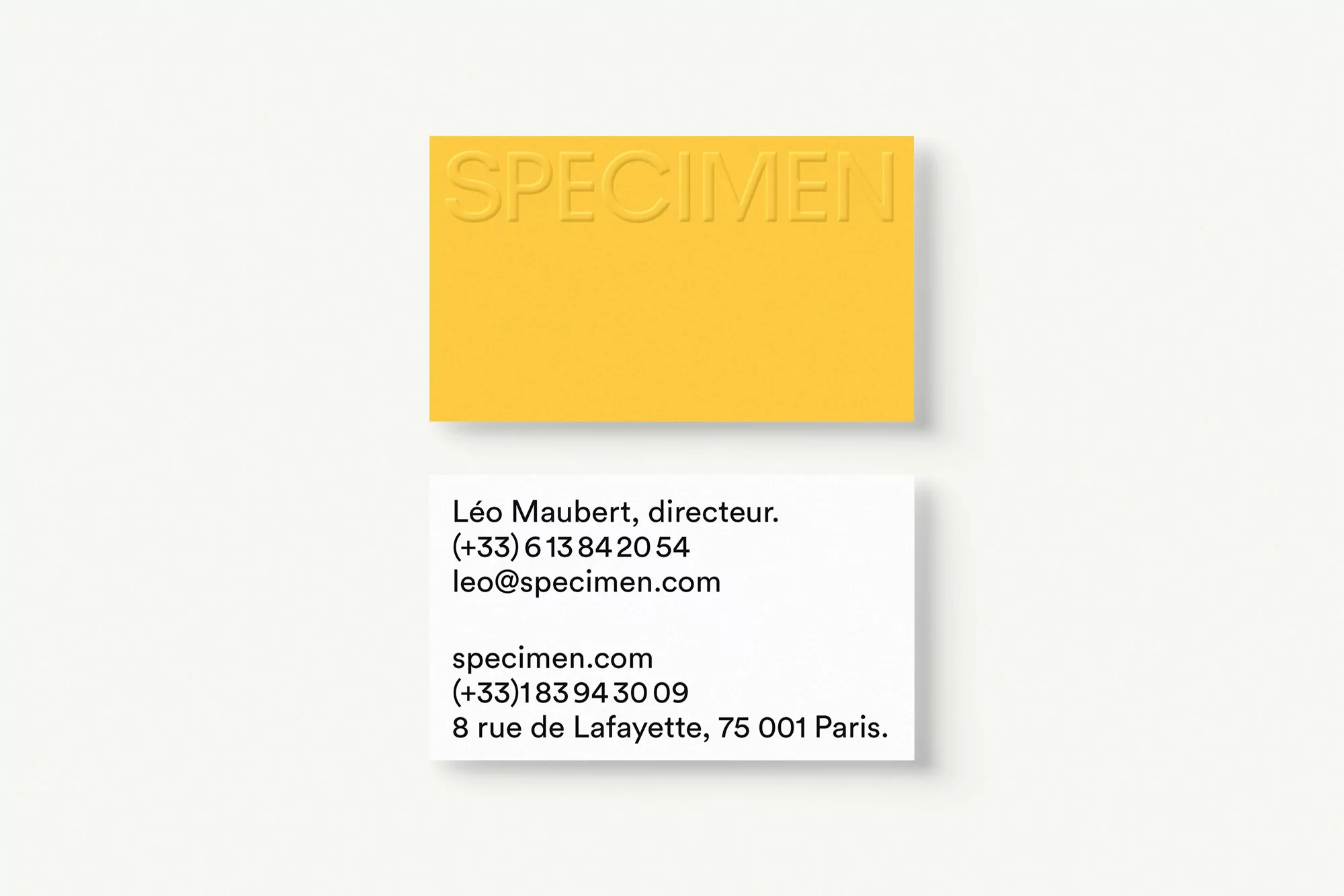 Two business cards on a white background. One is yellow with embossed text 'SPECIMEN' and the other is white with black contact information.