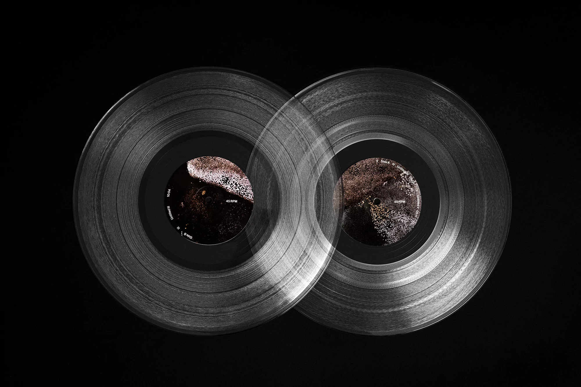 Two transparent vinyl records overlap slightly against a dark background, capturing a modern and minimalist aesthetic for music.