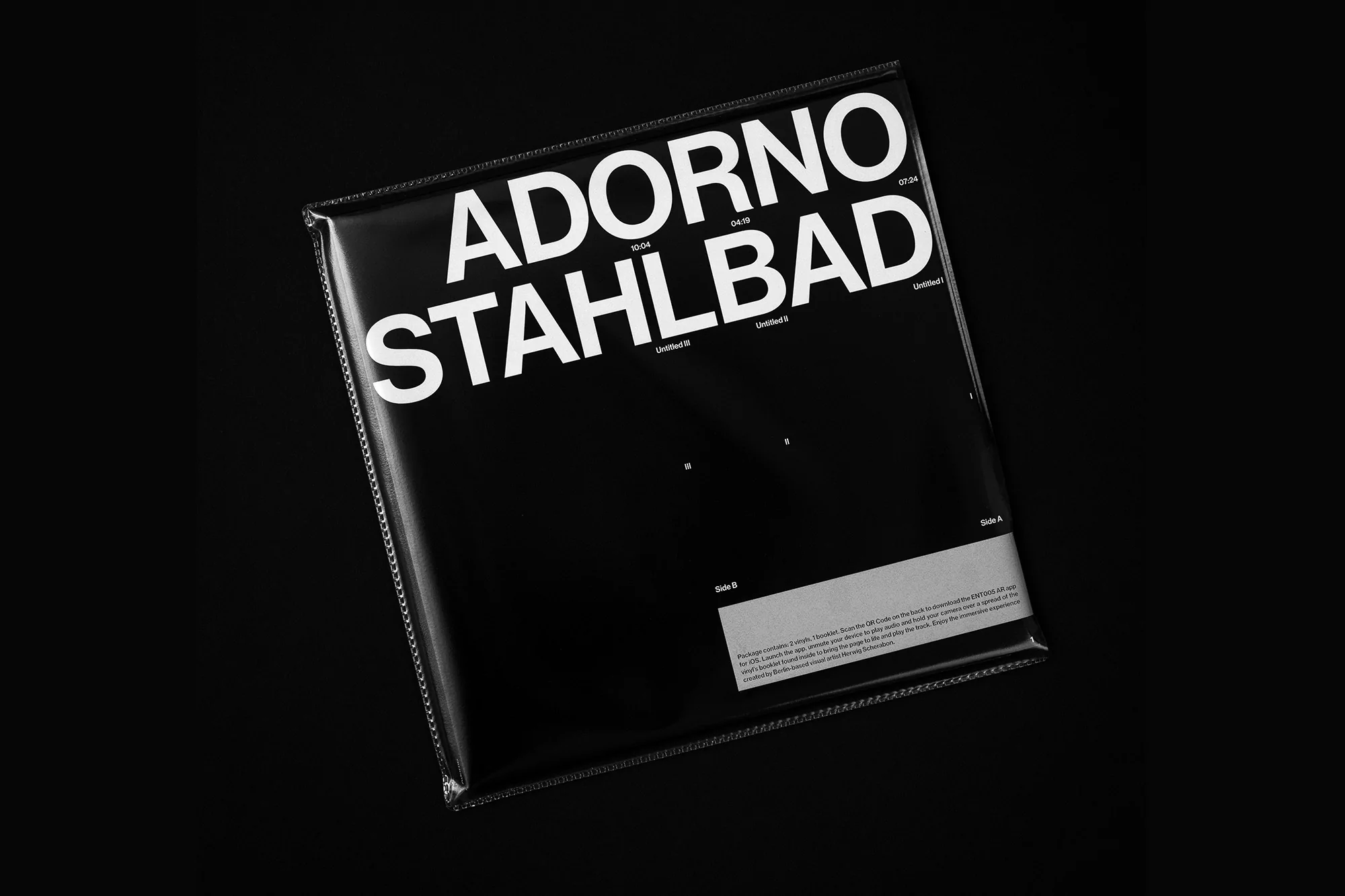 Black and white shot of a vinyl record cover titled 'Adorno Stahlbad' featuring minimalist design and bold typography in a studio setting.