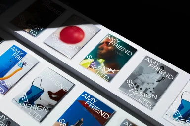 An arrangement of printed brand identity cards and booklets featuring the Amy Friend Set Design Ltd logo on white surfaces.
