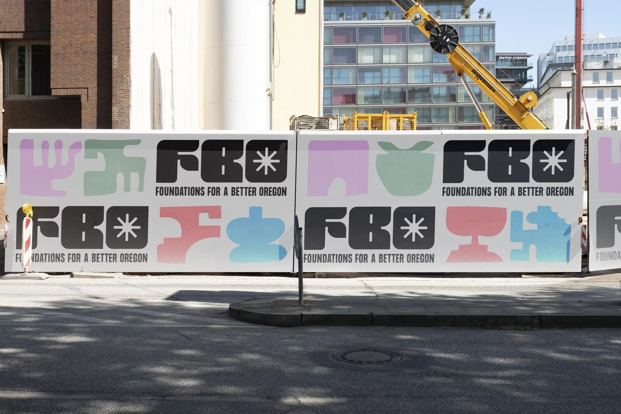Exterior view of construction site hoarding featuring colorful graphic designs and the text 'Foundations for a Better Oregon'.