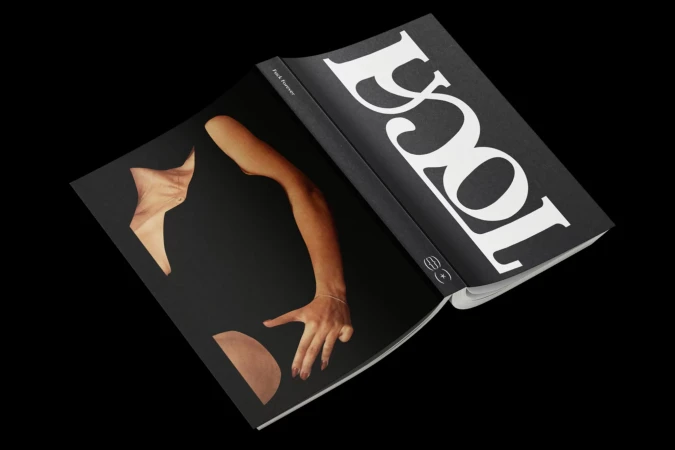 Open magazine displaying a photograph of a human arm, hand, and torso section against a black backdrop with bold, white typography.