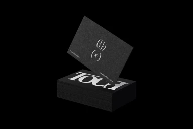 Black business cards featuring white typography and symbols stacked on a dark background with one card lifted above
