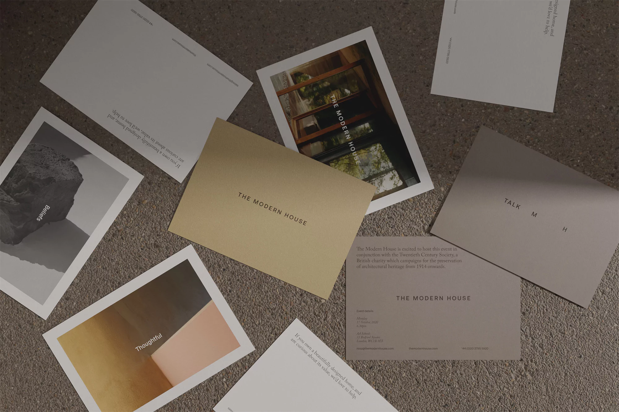 Scattered postcards with minimalist designs featuring architecture, landscapes, and typography on a textured neutral surface.
