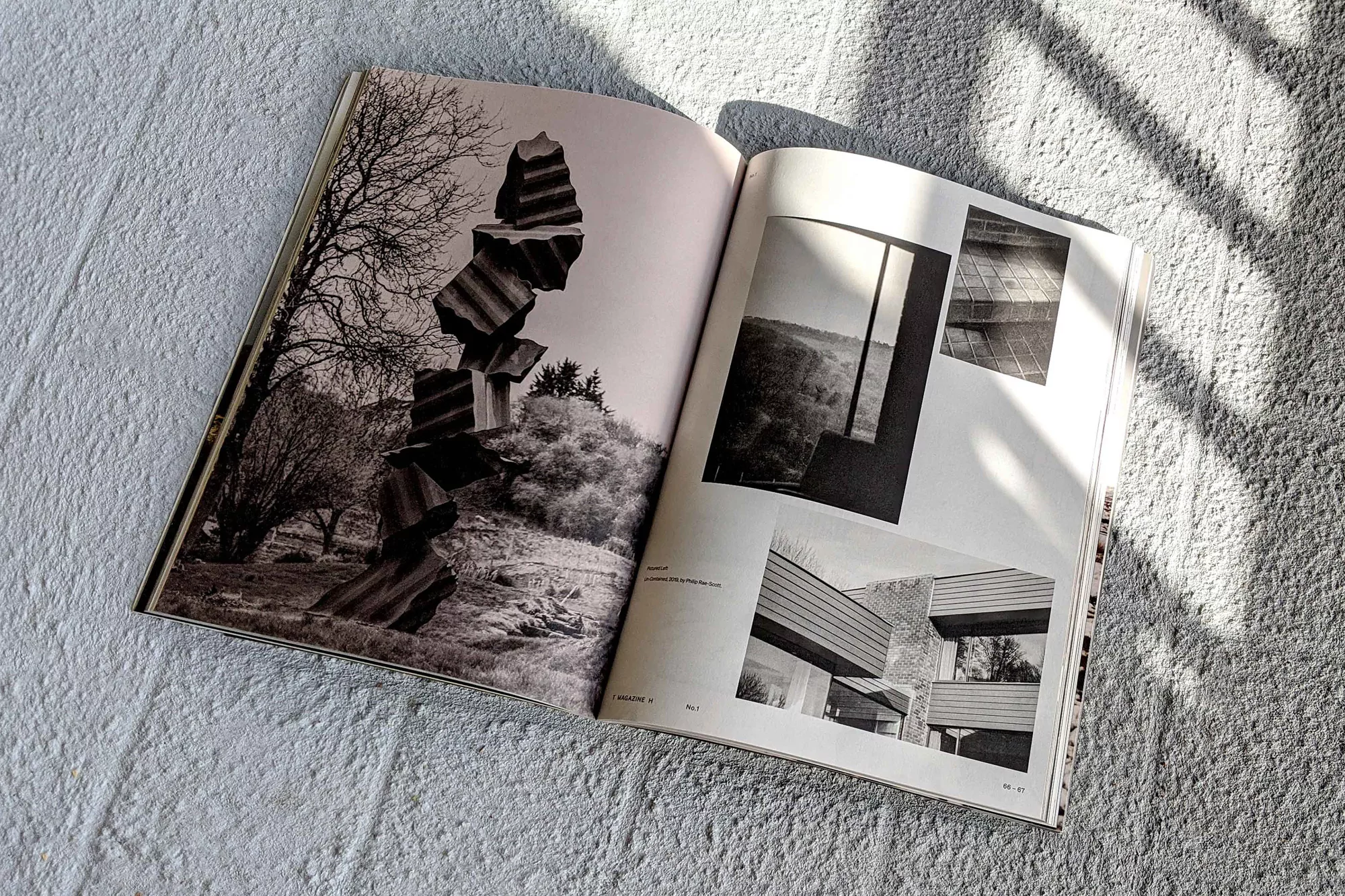 Open magazine displaying black and white architectural and landscape photography on a textured white background in natural light.