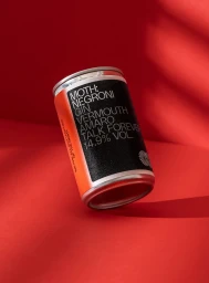 MOTH canned negroni cocktail on vibrant red background with angled studio lighting casting soft shadows
