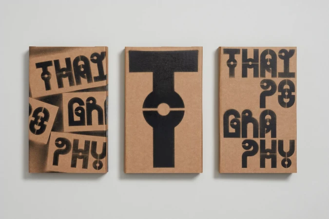 Three tan colored book covers with black stencil typography sit side by side against a white background in a studio shot.