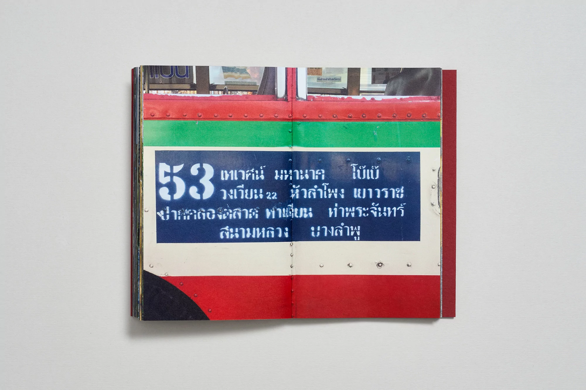 Close-up of an open book featuring a bus panel with route number '53' and text in Thai script on a white background.