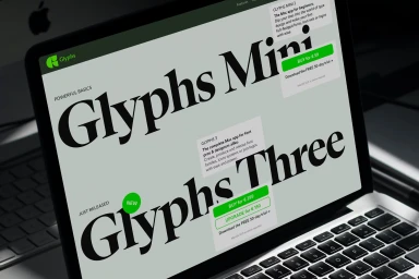 Close-up of a laptop screen displaying the Glyphs 3 font website with large serif typography and green accent buttons.