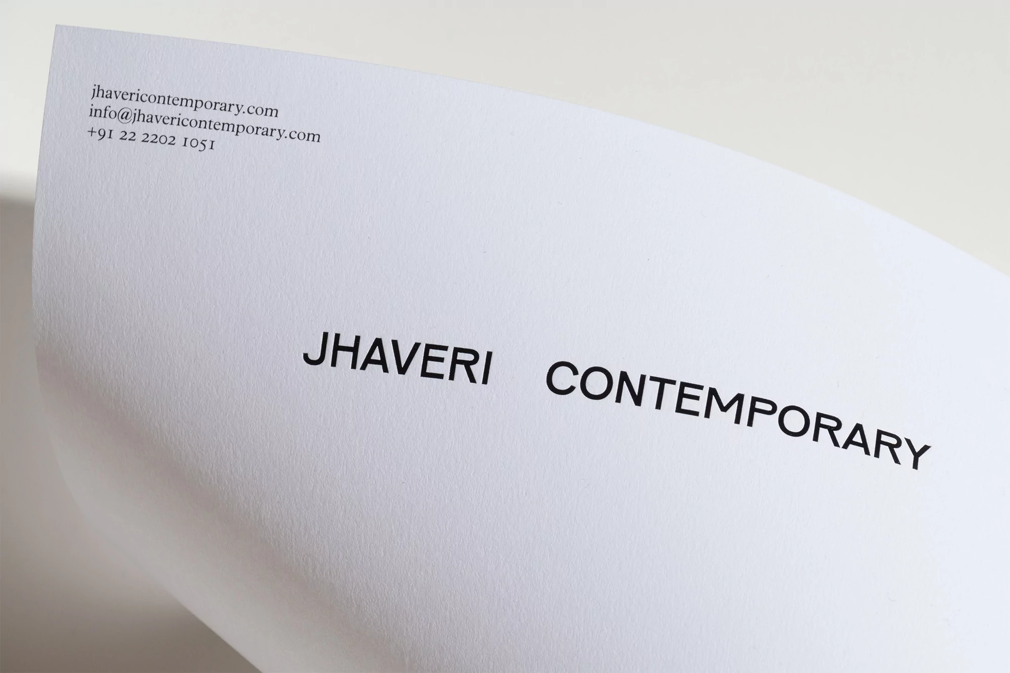 Close-up of a white paper with the text 'Jhaveri Contemporary' in black lettering, showcasing a gallery or art-related document.