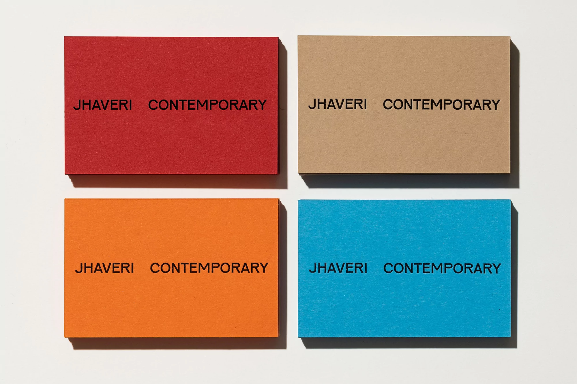 Four colorful cards with 'Jhaveri Contemporary' printed on a white surface, creating a simple, modern art display.