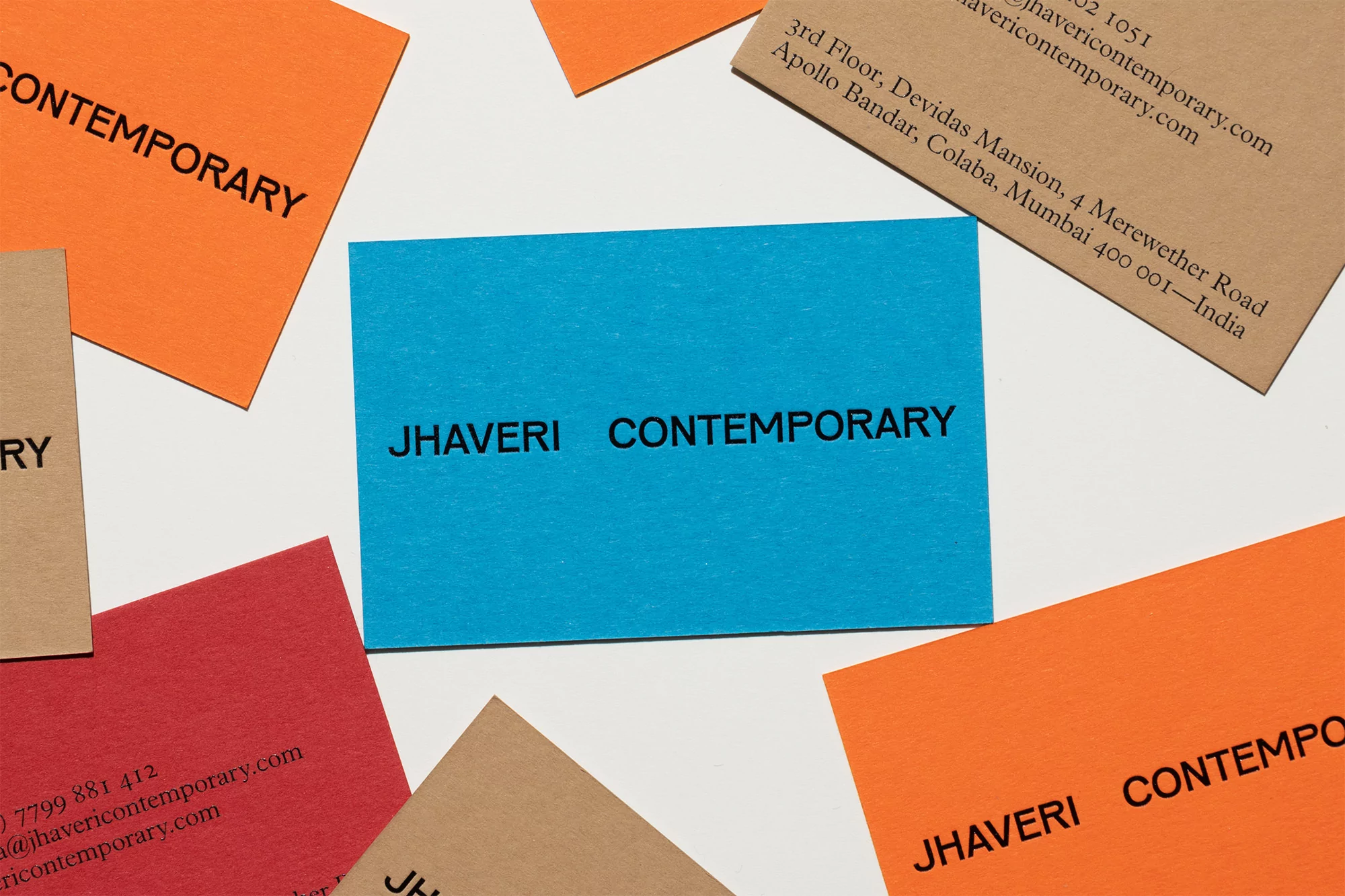 Business cards displaying the text 'Jhaveri Contemporary' in black on white, tan, blue, red, and orange against a white backdrop.