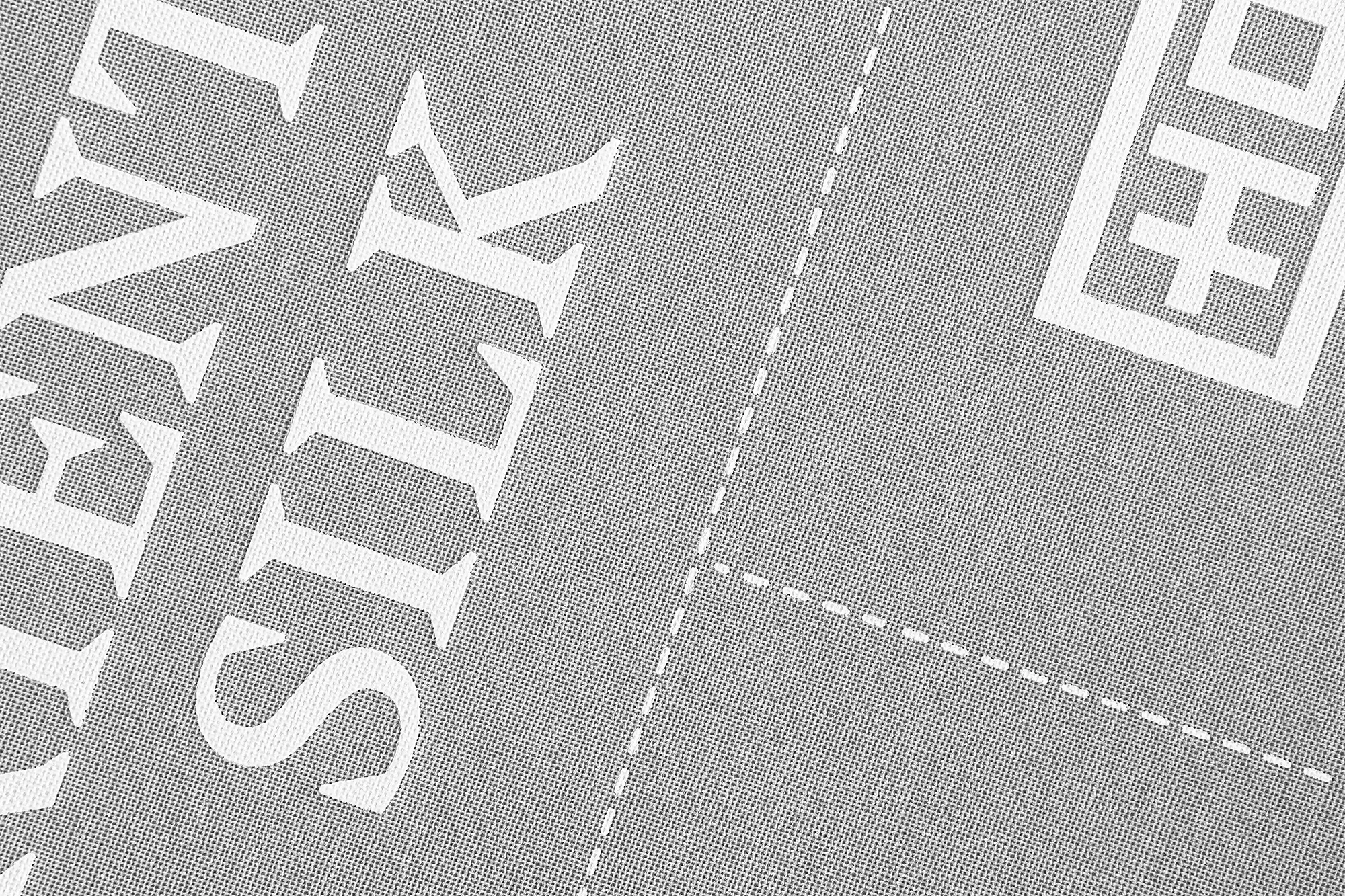 Close-up of grey fabric with white text reading 'TEXTILE EVENT SILK' and a white logo in the upper right corner.