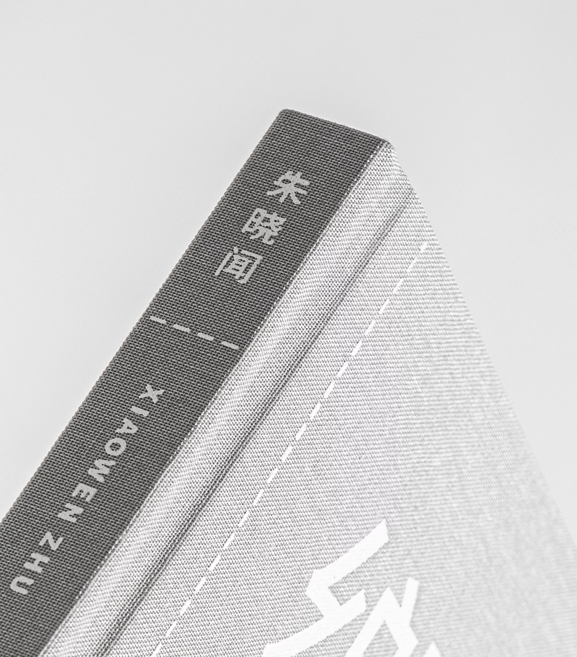 Close-up studio shot of a grey book with white text on its spine and cover against a bright neutral background.