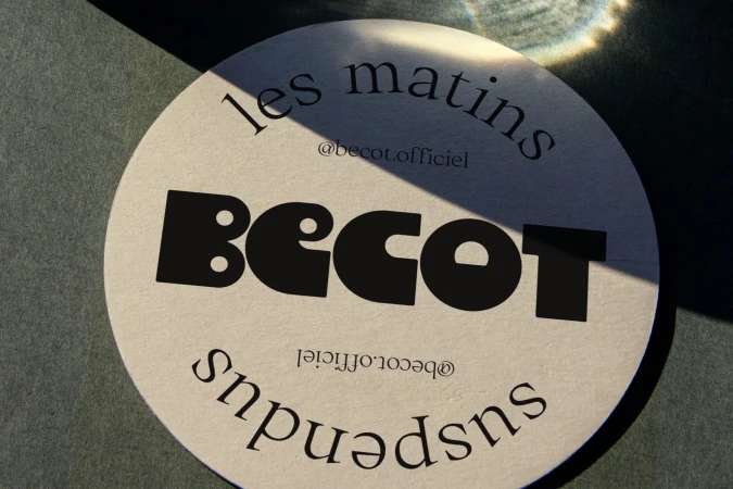 Abstract, close-up shot of a circular logo featuring the brand name 'Becot' and other text, set against a textured green background.