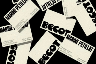 Scattered business cards with bold black typography on textured off-white paper against a dark background