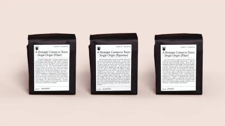 Three black coffee bags with white text labels displayed against a pale neutral background
