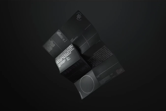 Promotional material from Gold University with text on the brochure in black and white and folded on top of a black background.
