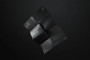 Folded black brochure displaying typography and geometric shapes against a dark background