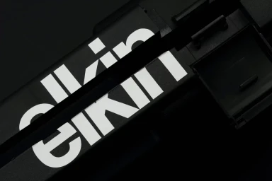 Close-up angled view of black packaging with bold white typography featuring Elkin Editions brand identity