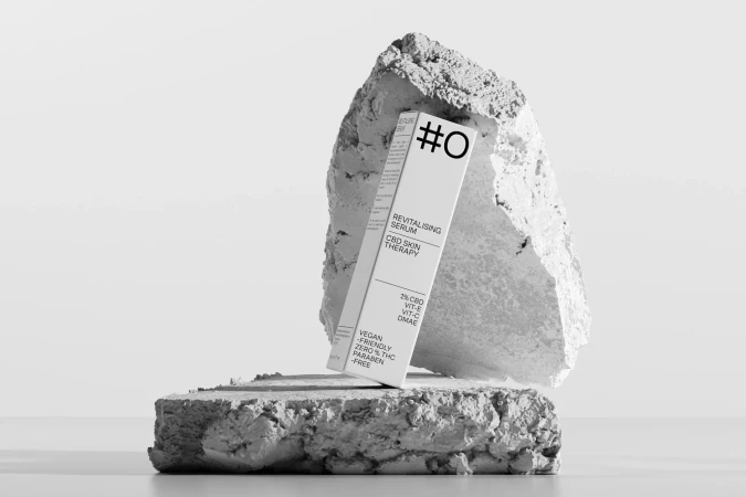 Serum product packaging sitting on rock platforms with a minimalist, clean aesthetic and monochrome color palette in a studio setting.