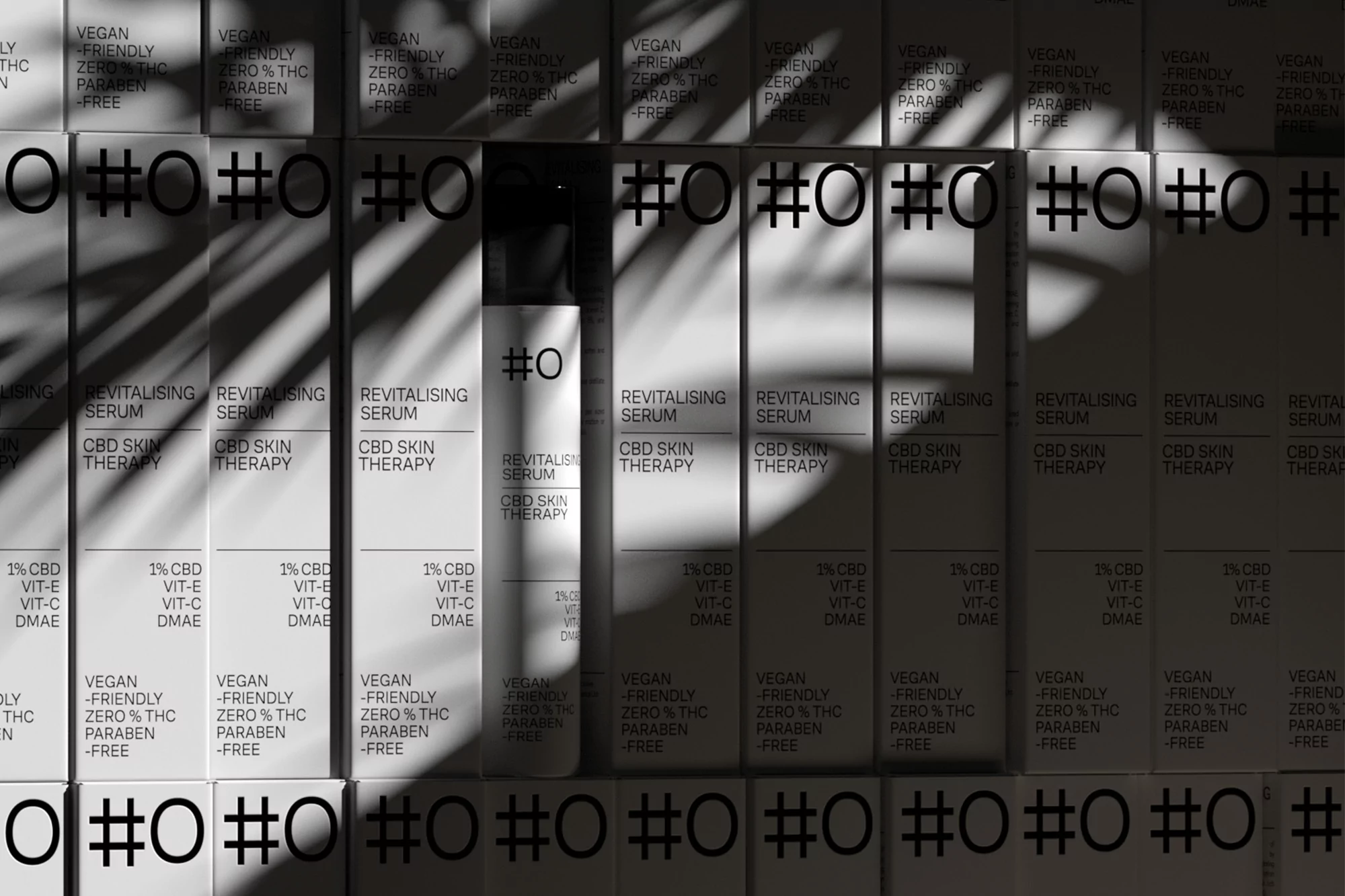 Product packaging for Hashtag Organics featuring revitalising serum bottles and boxes with palm leaf shadows.