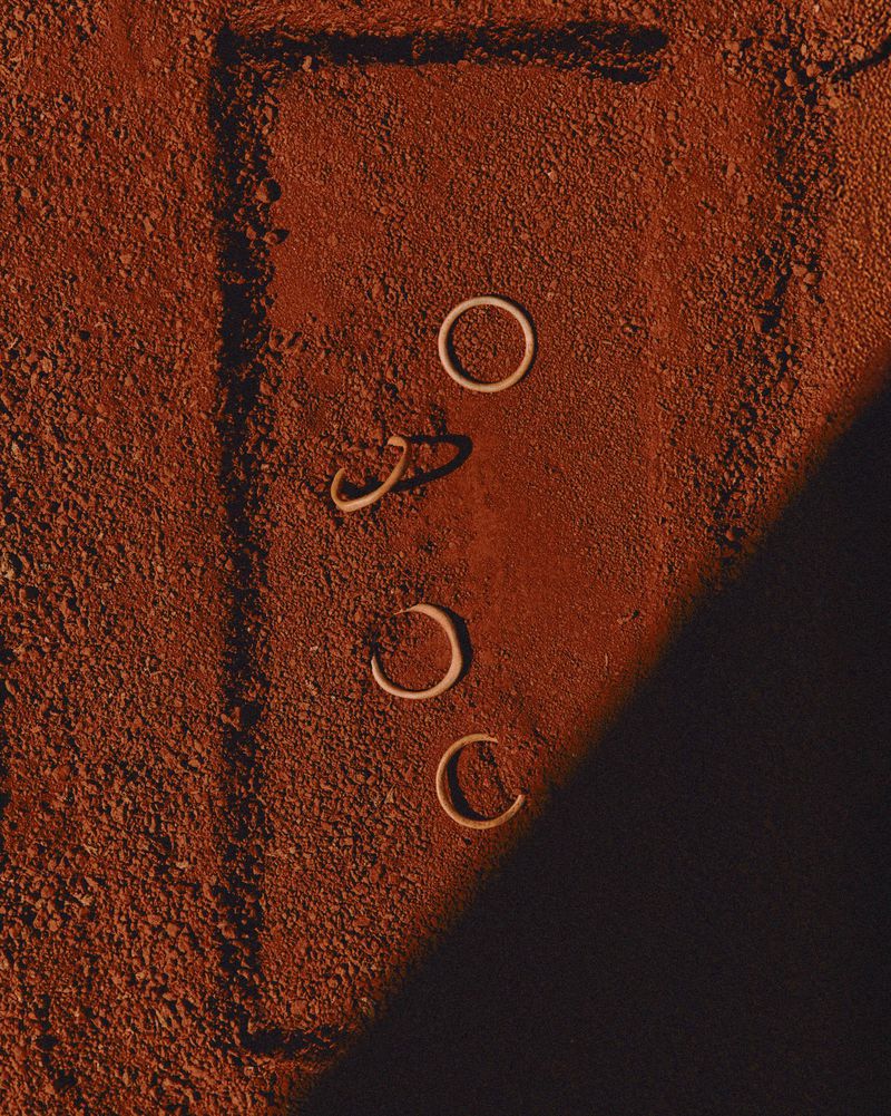 Aerial shot of three white rings and two partial rings on textured reddish-brown surface with rectangular line and shadows. 