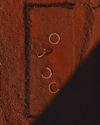 Four metal rings resting on a textured red earth terrain captured from an overhead perspective.