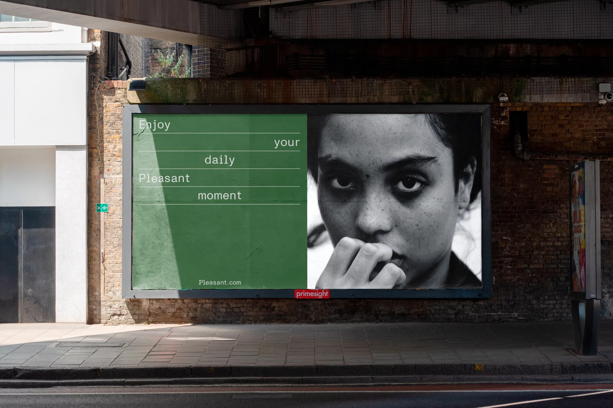 Outdoor billboard featuring a black and white portrait of a woman, alongside a green text panel reading 'Enjoy your daily pleasant moment'.